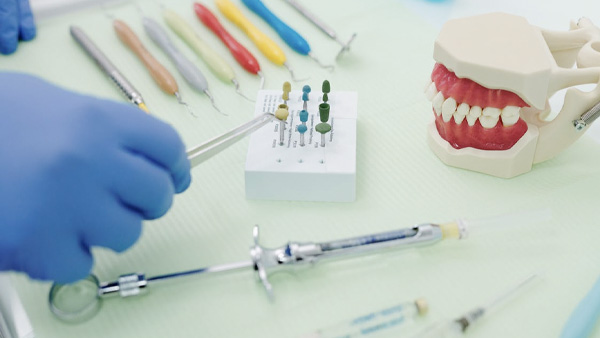 What Is Odontoma? Odontome is a term used for any tumour and/or tumour-like lesions that arise from tooth forming tissues. Odontoma is a hamartoma or say, local malformation made up of an abnormal mixture of dental cells and tissue. It is created as a result of terminated tooth formation, and accounts for around 22 per cent of odontogenic tumours. [1] Odontoma is often classified as benign (non-cancerous) odontogenic tumour. In simple terms if we conclude, odontoma is described as a tumour of the tooth formed due to overgrowth of dental cells and tissues. As a result of odontoma, the dental cells form variable amounts of dental contents like enamel, dentin, pulp and cementum which are organised in an abnormal pattern due to problems in their development, compared to their true structural growth. Types Of Odontoma Odontoma are mainly classified into four types by the WHO according to the stages of tooth development. They are: 1. Complex odontoma: When the dental tissues are arranged in an irregular mass with no relation to the primary teeth structure. [2] It accounts for 5-30 per cent of cases. 2. Compound odontoma: When the odontogenic tissues are arranged in an orderly pattern showing many teeth-like structures, but not biologically similar to normal teeth. [3] It accounts for 9-37 per cent of cases. 3. Odonto-ameloblastoma: It is a rare subtype of odontoma that resembles noncancerous tumours of the jaws both clinically and structurally, but contains dentine and enamel. 4. Ameloblastic fibro-odontoma: It is considered as an immature precursor of complex odontoma. Causes Of Odontoma The exact cause of tumours and cysts starting in the jaws is still unknown. Studies say that odontoma starts due to proliferation of cells and tissues which are involved in normal tooth development. This could be the result of some genetic syndromes, environmental factors or due to both the factors. Symptoms Of Odontoma Odontomas are usually asymptomatic in the beginning, but there are many clinical signs that could help indicating odontomas such as: [4] Retention of deciduous teeth. Lack of eruption of permanent teeth. Impacted teeth Displacement of teeth from its position. Expansion of outer jaw bone. Numbness in the lower lip area. Swelling in the jaws or near the jaws area where there is tumour. Evidence of infection. Diagnosis Of Odontoma As aforementioned, odontomas are mainly asymptomatic and are often diagnosed during the routine dental checkups. Some of the diagnostic methods to diagnose odontoma include: [5] Radiography: It helps get the proper image of the tissues, bone and vessels of the jaws to see for any signs of tumour. X-ray: It also helps get images of tumours, if present. Patient history and physical examination: It helps the patient know whether they had any history of odontoma or any cancer, followed by examining the areas near the teeth. Treatments Of Odontoma The treatment of odontoma may differ from person to person depending on the severity, symptoms, stage of growth and type of odontogenic tumour. The primary treatment for odontoma is surgery that includes removing the jaw tumours and cysts which are nearby teeth and jawbone. [6] Large lesions sometimes require adding the bone to fill the gap caused by its removal. The method is often followed by medical therapy such as use of medications to reduce pain and swelling in the area. Supportive care along with the treatment helps improve the quality of life, by helping in swallowing, speech and replacing the missing teeth. To Conclude There’s no exact cause for the development of tumour and it can occur due to many factors. Routine checkups can help diagnose any cancer type at an early stage and treat the condition successfully.