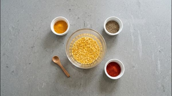 Soaked chana dal in a glass bowl with spices arranged in small containers nearby Soaked chana dal in a glass bowl with spices arranged in small containers nearby