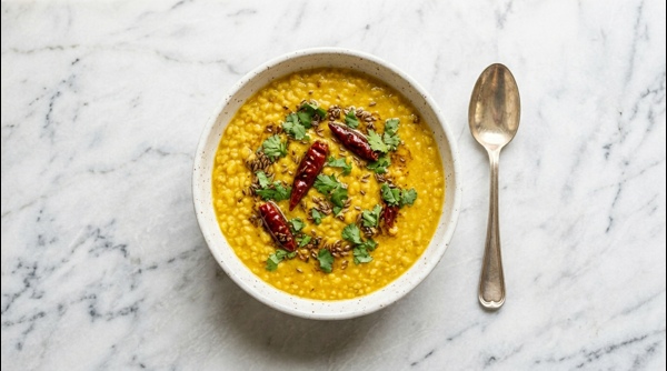 A steaming bowl of yellow Moong Dal topped with fresh coriander and sizzling tadka