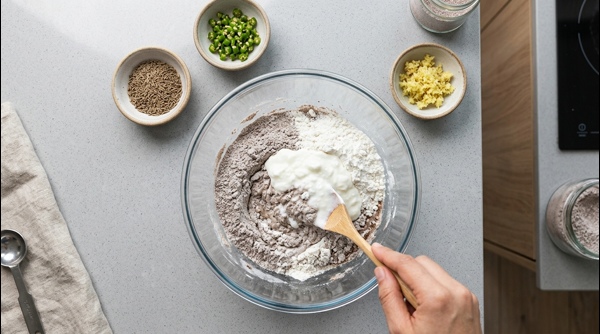 Whisking a thin brown ragi dosa batter in a glass bowl Whisking a thin brown ragi dosa batter in a glass bowl