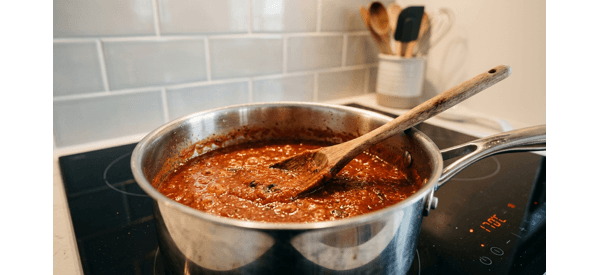 Thick red pizza sauce in a modern pot with fresh basil leaves on top Thick red pizza sauce in a modern pot with fresh basil leaves on top