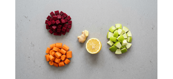 Chopped red beetroots, orange carrots, and green apples arranged neatly on a white quartz countertop Chopped red beetroots, orange carrots, and green apples arranged neatly on a white quartz countertop
