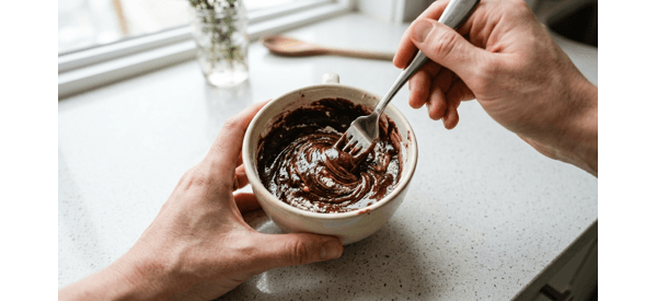 Mixing the liquid ingredients into the dry mug cake batter with a fork Mixing the liquid ingredients into the dry mug cake batter with a fork