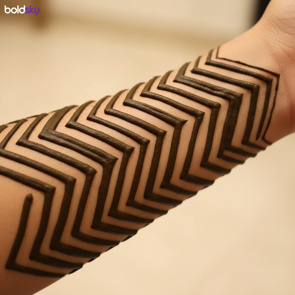 Left forearm bold chevron mehndi pattern.